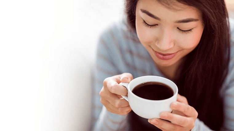 Young woman holding a cup of black coffee